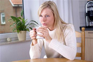 Женщина пьет чай за столом