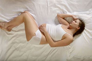 Беременная девушка лежит на кровати