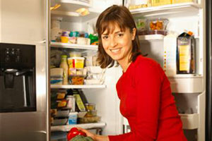 Женщина сидит перед холодильником