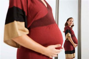 Беременная женщина смотрит в зеркало