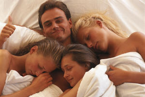 Мужчина в постели с тремя женщинами