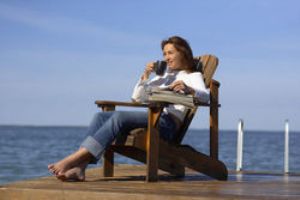Женщина сидит на берегу и пьет чай