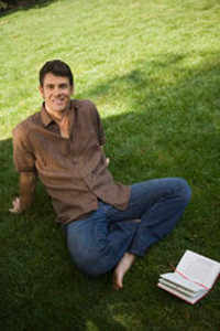 Мужчина с книжкой на зеленой траве
