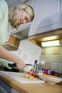 Женщина чистит овощи над кухонной стойкой