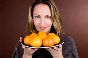 Женщина держит блюдо с мандаринами