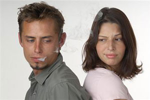 Мужчина курит в лицо девушке