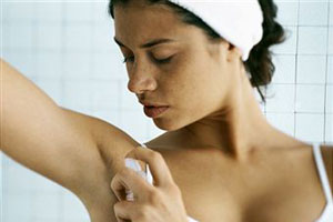 Женщина пользуется дезодорантом