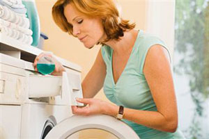 Женщина заправляет стиральную машинку