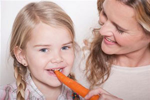 Женщина кормит дочку морковью