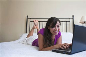 Девушка работает на кровате в ноутбуке