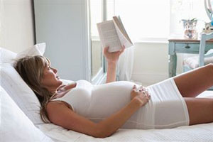 Беременная женщина на постеле