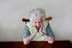 Пожилая женщина сидит за столом