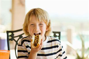 Мальчик ест хот-дог