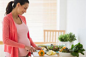 Беременная женщина режет овощи