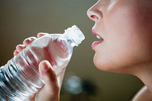 Женщина пьет воду из бутылки