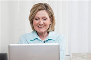 Пожилая женщина сидит за компьютером