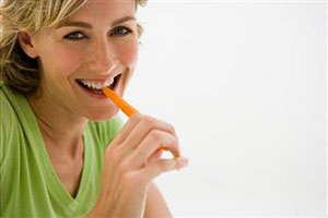 Женщина ест морковь