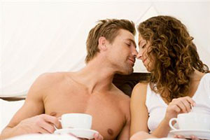 Мужчина и женщина пьют кофе в постеле