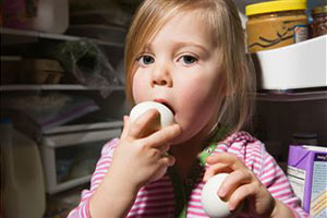 Девочка ест яйцо