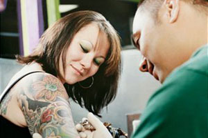 Мастер делает татуировку девушке