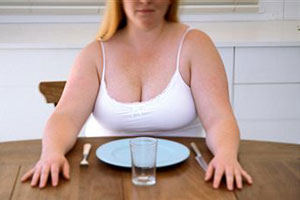Толстая девушка сидит за столом