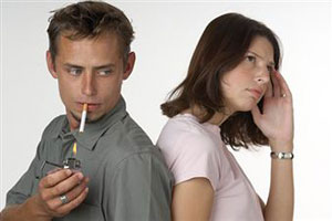 Молодой человек закуривает сигарету при девушке