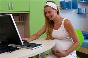 Беременная девушка сидит за компьютером