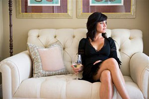 Девушка сидит на диване и пьет вино