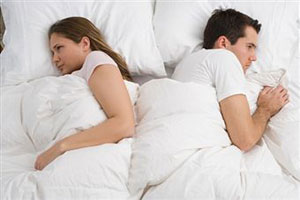 Мужчина и женщина лежат на кровати спинами друг к другу