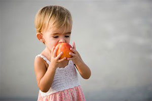 Маленькая девочка кушает апельсин