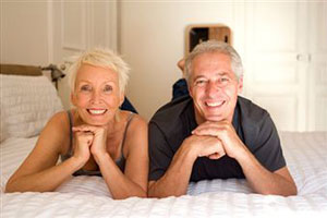 Мужчина и женщина улыбаются лежа на кровати
