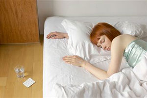 Девушка лежит на кровати рядом со снотворным