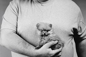Толстый мужчина держит щенка на руках