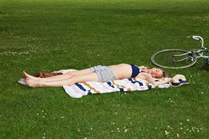 Девушка спит на зеленом поле после занятия спортом