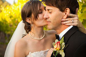 Новоиспеченная невеста целует в щеку своего жениха