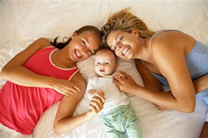 Две лезбиянки лежат на кровати с ребенком