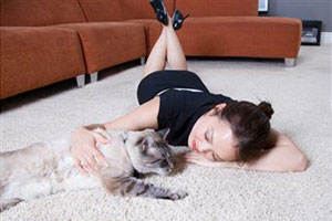 Девушка лежит на ковре с кошкой