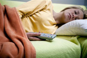 Женщина спит на диване с пультом от телевизора в руках