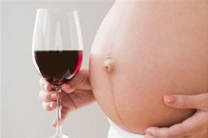 Беременная женщина держит бокал с вином