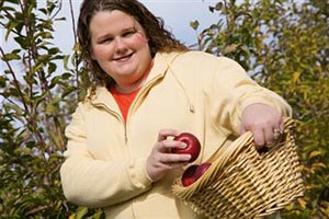 Толстая женщина собирает яблоки