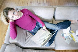 Девушка с ноутбуком сидит на диване