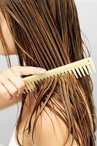 Женщина расчесывает мокрые волосы