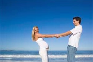 Беременная женщина и мужчина на берегу