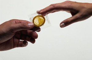 Мужская и женская руки держат презерватив