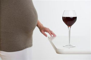Беременная женщина держит бокал вина