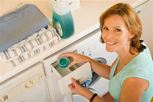 Женщина закладывает белье в стиральную машину