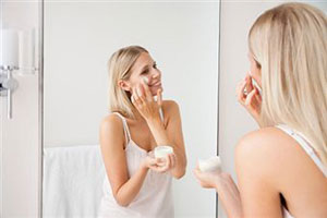 Женщина наносит крем перед зеркалом
