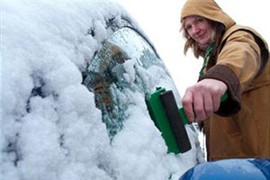 Девушка очищает машину от снега