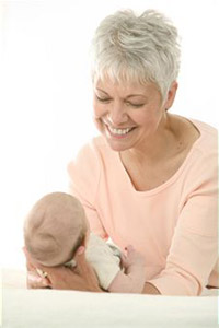 Женщина в возрасте держит на руках младенца