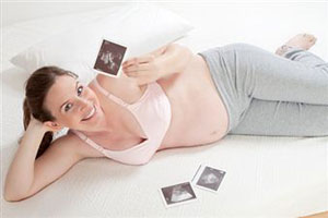 Беременная женщина смотрит на снимкм УЗИ